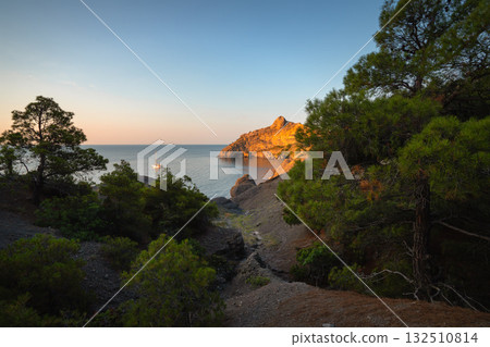 Rock and sea at sunset, yacht near the shore and green pines Rock and sea at sunset, yacht near the shore and green pines 132510814