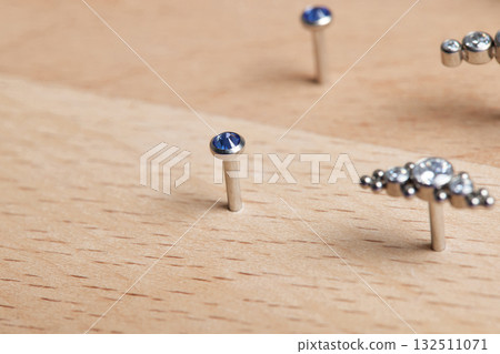 Beautiful piercing jewelry on wooden display. Macro shot. Selective focus. Beautiful piercing jewelry on wooden display. Macro shot. Selective focus. 132511071