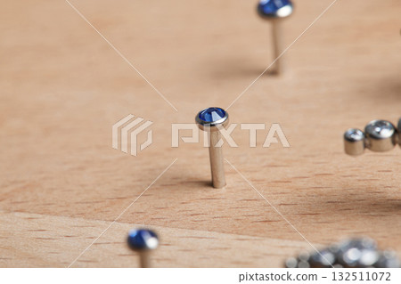 Beautiful piercing jewelry on wooden display. Macro shot. Selective focus. Beautiful piercing jewelry on wooden display. Macro shot. Selective focus. 132511072