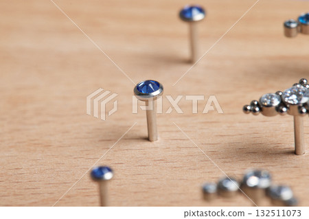 Beautiful piercing jewelry on wooden display. Macro shot. Selective focus. 132511073