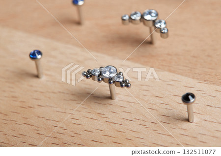 Beautiful piercing jewelry on wooden display. Macro shot. Selective focus. Beautiful piercing jewelry on wooden display. Macro shot. Selective focus. 132511077