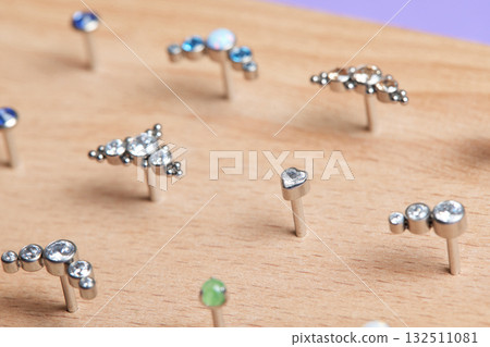 Beautiful piercing jewelry on wooden display. Macro shot. Selective focus. Beautiful piercing jewelry on wooden display. Macro shot. Selective focus. 132511081