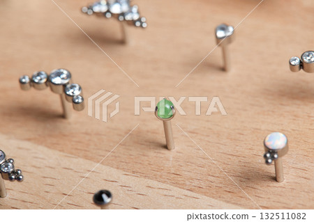 Beautiful piercing jewelry on wooden display. Macro shot. Selective focus. Beautiful piercing jewelry on wooden display. Macro shot. Selective focus. 132511082