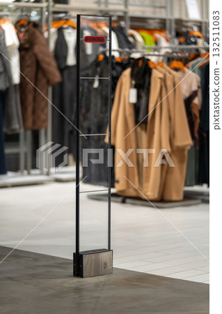 A sleek, transparent security gate stands at the entrance of a modern clothing store. A sleek, transparent security gate stands at the entrance of a modern clothing store. 132511083