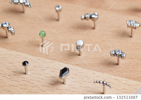 Beautiful piercing jewelry on wooden display. Macro shot. Selective focus. Beautiful piercing jewelry on wooden display. Macro shot. Selective focus. 132511087