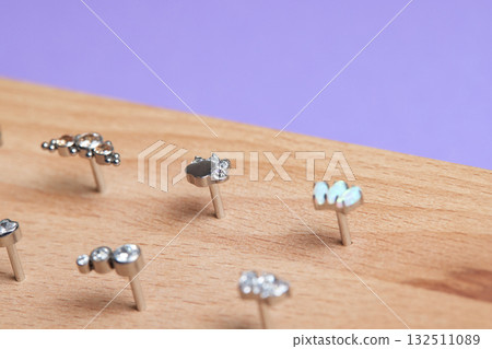 Beautiful piercing jewelry on wooden display. Macro shot. Selective focus. 132511089