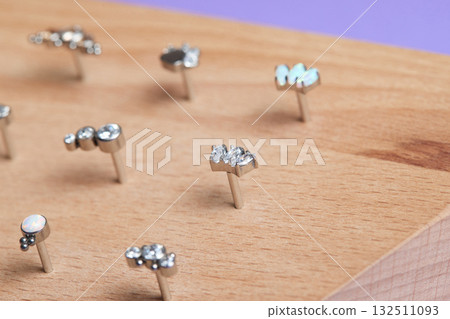 Beautiful piercing jewelry on wooden display. Macro shot. Selective focus. Beautiful piercing jewelry on wooden display. Macro shot. Selective focus. 132511093