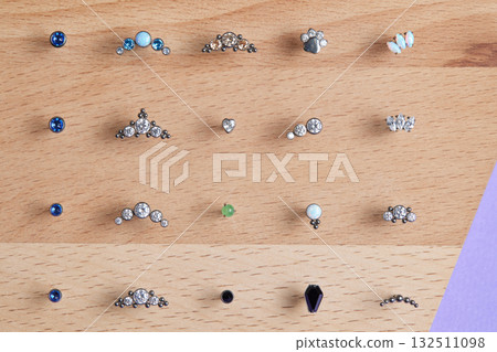 Beautiful piercing jewelry on wooden display. Macro shot. Selective focus. Beautiful piercing jewelry on wooden display. Macro shot. Selective focus. 132511098