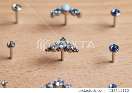 Beautiful piercing jewelry on wooden display. Macro shot. Selective focus. Beautiful piercing jewelry on wooden display. Macro shot. Selective focus. 132511110