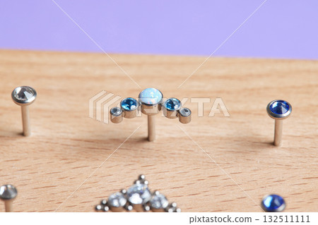 Beautiful piercing jewelry on wooden display. Macro shot. Selective focus. Beautiful piercing jewelry on wooden display. Macro shot. Selective focus. 132511111