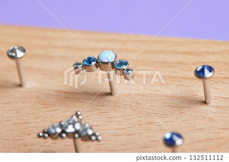Beautiful piercing jewelry on wooden display. Macro shot. Selective focus. Beautiful piercing jewelry on wooden display. Macro shot. Selective focus. 132511112