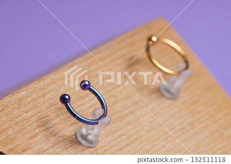 Beautiful piercing jewelry on wooden display. Macro shot. Selective focus. Beautiful piercing jewelry on wooden display. Macro shot. Selective focus. 132511118
