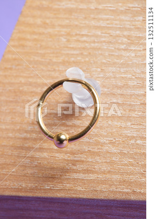 Beautiful piercing jewelry on wooden display. Macro shot. Selective focus. Beautiful piercing jewelry on wooden display. Macro shot. Selective focus. 132511134