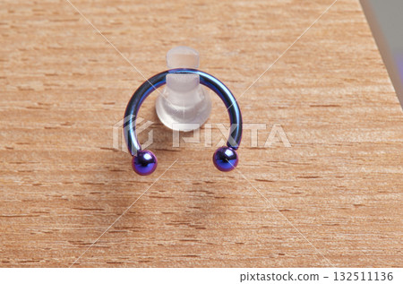 Beautiful piercing jewelry on wooden display. Macro shot. Selective focus. Beautiful piercing jewelry on wooden display. Macro shot. Selective focus. 132511136