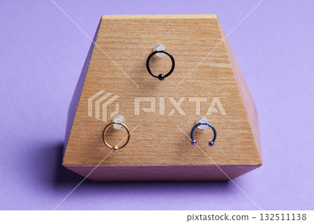 Beautiful piercing jewelry on wooden display. Macro shot. Selective focus. Beautiful piercing jewelry on wooden display. Macro shot. Selective focus. 132511138