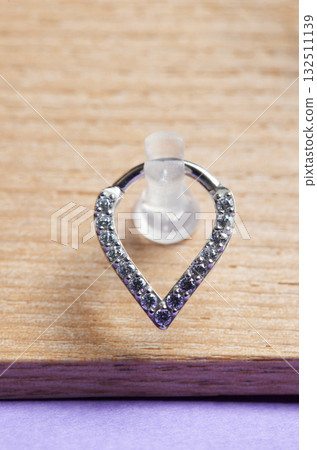 Beautiful piercing jewelry on wooden display. Macro shot. Selective focus. Beautiful piercing jewelry on wooden display. Macro shot. Selective focus. 132511139
