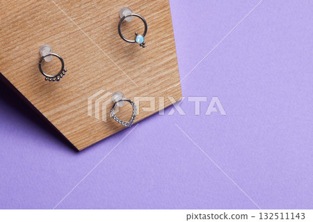 Beautiful piercing jewelry on wooden display. Macro shot. Selective focus. 132511143
