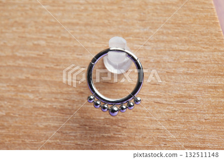 Beautiful piercing jewelry on wooden display. Macro shot. Selective focus. Beautiful piercing jewelry on wooden display. Macro shot. Selective focus. 132511148
