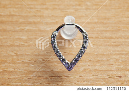 Beautiful piercing jewelry on wooden display. Macro shot. Selective focus. Beautiful piercing jewelry on wooden display. Macro shot. Selective focus. 132511150