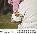 big bitten bagel in child's hand. adult man holds child in his arms 132511162