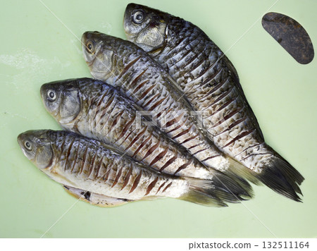 Raw peeled and gutted crucian carp on a green board. Raw peeled and gutted crucian carp on a green board. 132511164