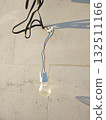 The light bulb hangs against a light concrete wall, illuminated by sunlight 132511166