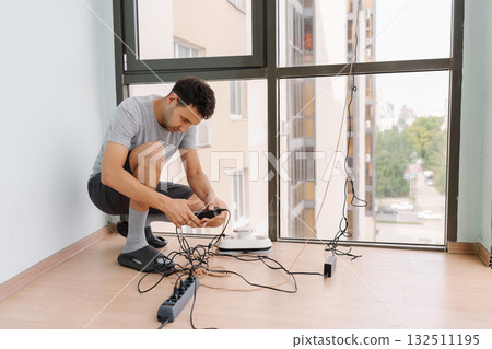 Professional window technician male managing robotic cleaning equipment, preparing automated system for servicing high-rise building exterior, demonstrating advanced maintenance technology. 132511195