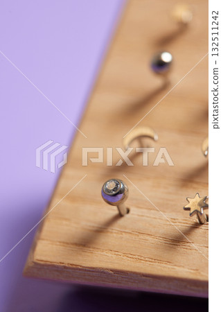 Beautiful piercing jewelry on wooden display. Macro shot. Selective focus. Beautiful piercing jewelry on wooden display. Macro shot. Selective focus. 132511242