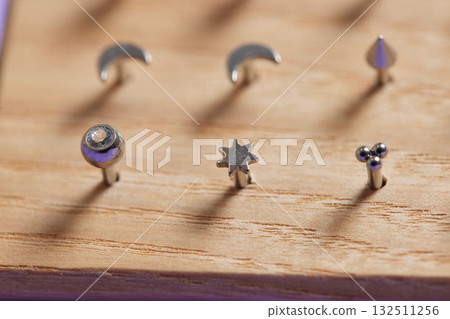 Beautiful piercing jewelry on wooden display. Macro shot. Selective focus. Beautiful piercing jewelry on wooden display. Macro shot. Selective focus. 132511256