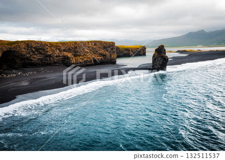 View on Kirkjufjara beach and Arnardrangur cliff. Location Atlantic ocean, Iceland, Europe. 132511537