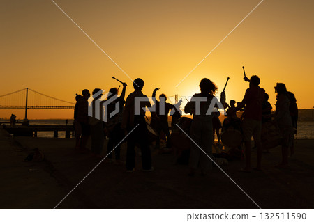 A silhouette of drum players musicians against a sunset 132511590