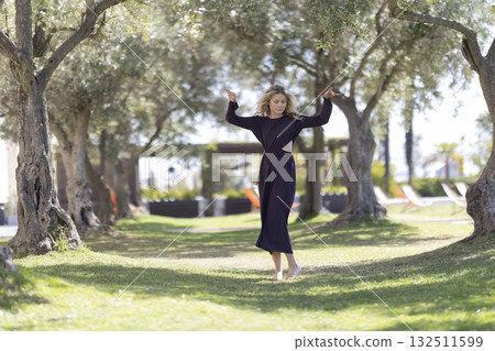 Barefoot woman dancing with graceful movement in a garden Barefoot woman dancing with graceful movement in a garden 132511599