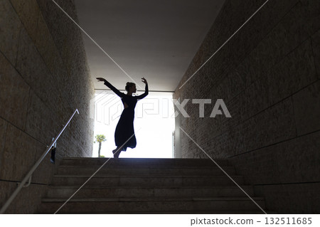 Dancer silhouetted in light exiting dark tunnel Dancer silhouetted in light exiting dark tunnel 132511685