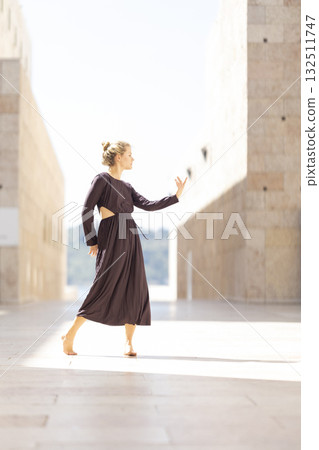 Young woman dancing gracefully between modern buildings 132511747