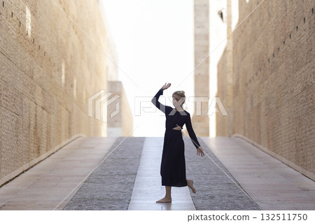 Woman dancing freely in stone passage towards light Woman dancing freely in stone passage towards light 132511750