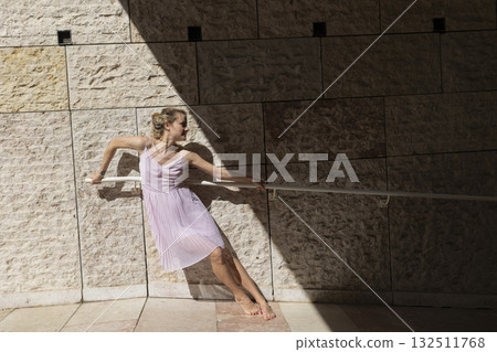 Woman ballerina dancing barefoot holding railing outdoors Woman ballerina dancing barefoot holding railing outdoors 132511768