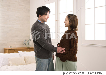 A young couple standing by the window, a pregnant woman 132511965