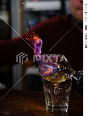 The bartender makes flame over a cocktail with orange peel close up 132512091