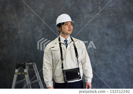 A young man wearing work clothes and a helmet A young man wearing work clothes and a helmet 132512292
