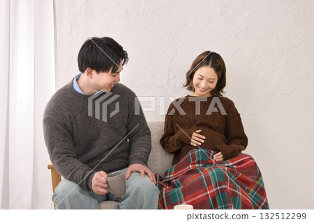 一對年輕夫婦在沙發上休息，孕婦 132512299