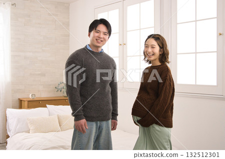 一對年輕夫婦站在窗邊,一名孕婦 一對年輕夫婦站在窗邊,一名孕婦 132512301