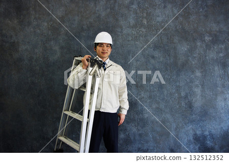 一名身穿工作服、頭戴安全帽的年輕人 一名身穿工作服、頭戴安全帽的年輕人 132512352