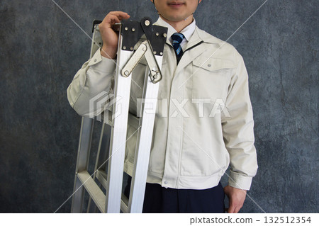 身穿工作服的年輕男子手持三腳架 身穿工作服的年輕男子手持三腳架 132512354