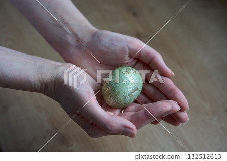Hands holding green decorative egg with golden shine. Hands holding green decorative egg with golden shine. 132512613
