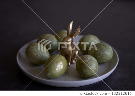 Easter eggs and rabbit figurine on white plate. Easter eggs and rabbit figurine on white plate. 132512615