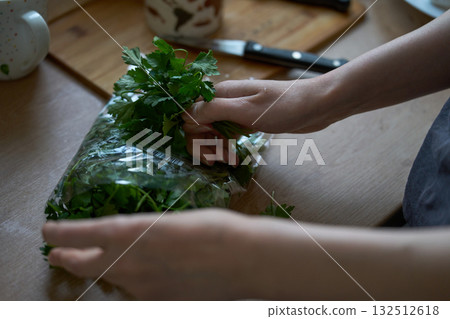 Fresh parsley in hands over kitchen surface. 132512618