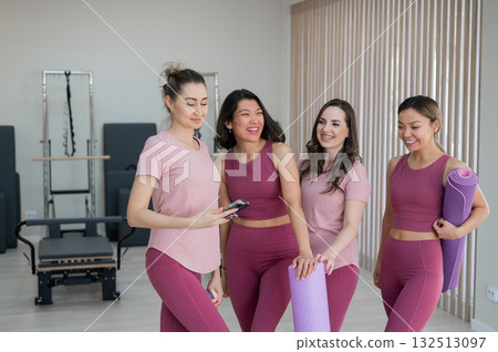 A trainer adjusts women on a reformer. A trainer adjusts women on a reformer. 132513097