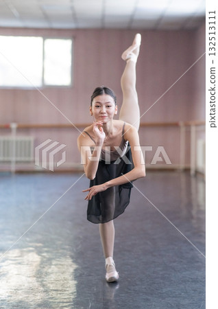 Graceful Asian ballerina in a beige bodysuit and black skirt is rehearsing in a dance class. Graceful Asian ballerina in a beige bodysuit and black skirt is rehearsing in a dance class. 132513111