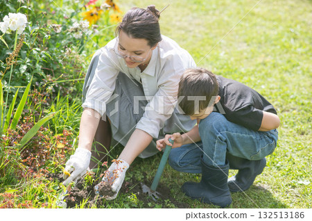 Caucasian woman tending her garden with her sons. Caucasian woman tending her garden with her sons. 132513186