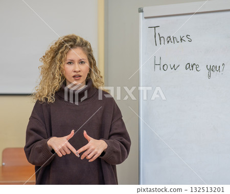 Caucasian female teacher communicates in Russian sign language with students. Caucasian female teacher communicates in Russian sign language with students. 132513201